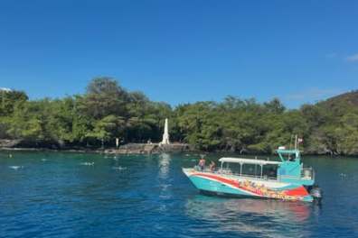 Colorful boat in blue water near a green shoreline with a white monument.